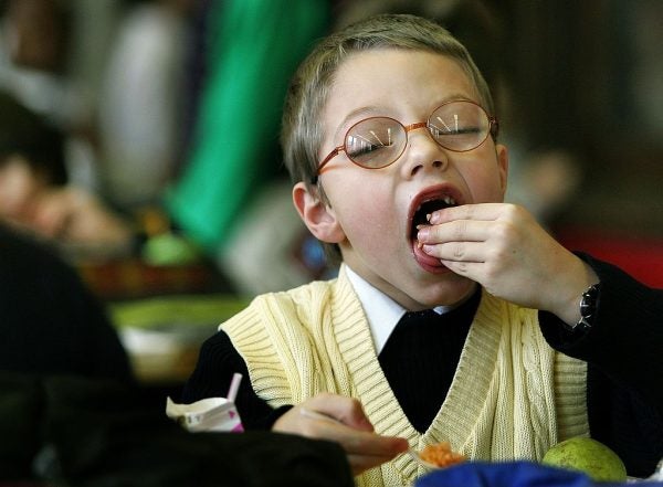 kid with glasses chows down at school lunch with school lunch hacks